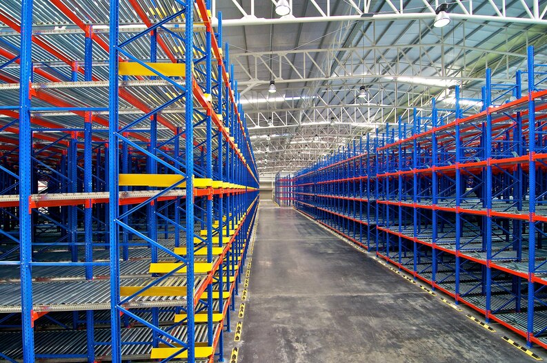 Industrial warehouse featuring blue and orange pallet racking systems with multiple shelves, designed for efficient storage solutions in Arlington, TX.