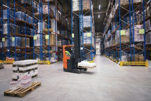 Warehouse interior with pallet racks, forklift in operation, and stacked pallets, illustrating efficient storage solutions for Dallas Pallet Racking services.