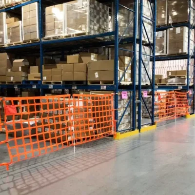 Warehouse aisle with orange safety netting and stacked cardboard boxes on pallet racks, illustrating safety measures in storage systems at Dallas Pallet Racking in Arlington, TX.
